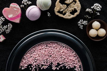 Obraz na płótnie Canvas top view of pink sea salt, handmade soaps and sponge on black