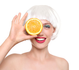 Young woman with wig and orange half on white background