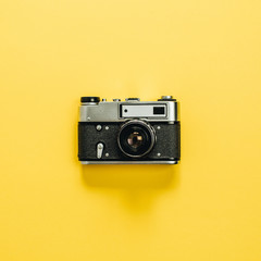 Fototapeta premium Vintage retro camera isolated on yellow background. Flat lay, top view.