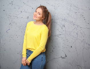 Beautiful young woman against grey wall