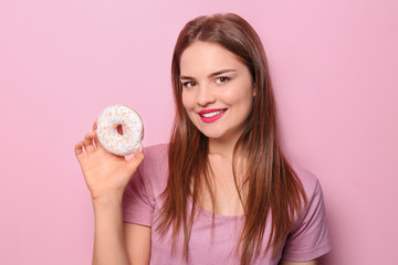 Attractive girl posing with doughnut on color background