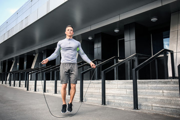 Sporty young man jumping rope outdoors