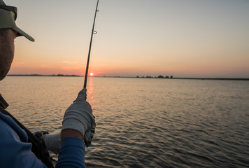 A fisherman fishing at dawn on a river. Close-up.
