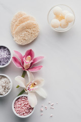 Fototapeta na wymiar beautiful orchid flowers, sea salt in bowls and sponges on white background