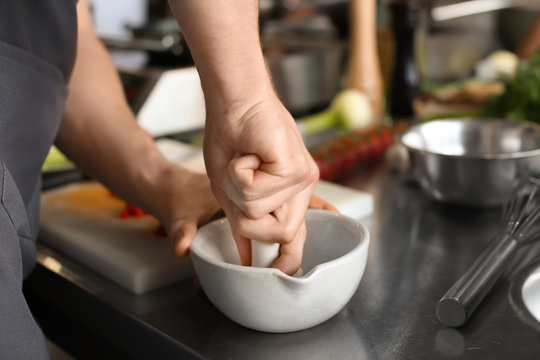 Man pounding spices in mortar during cooking classes