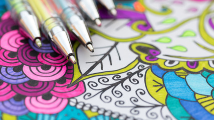 Adult coloring book, new stress relieving trend. Art therapy, mental health, creativity and mindfulness concept. Adult coloring page with pastel colored gel pen close up. - obrazy, fototapety, plakaty