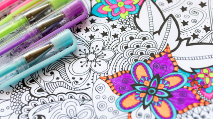 Adult coloring book, new stress relieving trend. Art therapy, mental health, creativity and mindfulness concept. Adult coloring page with pastel colored gel pen close up.