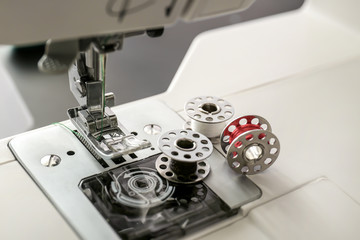 Presser foot and needle of modern sewing machine with spools, closeup