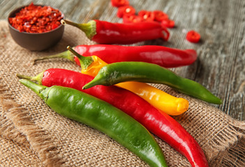 Fresh and granulated chili pepper on wooden background