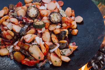 Cooking vegetables and food over an open fire on outdoor.