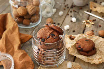Glass jar with delicious chocolate chip cookies on wooden table