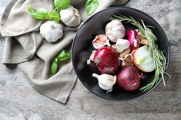 Composition with onions, garlic and herbs on wooden background