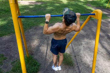 A young man is engaged on a horizontal bar in the park