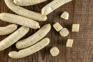 Lot of whole lot of slices lot of pieces of bavarian white sausage stack flatlay on brown wood