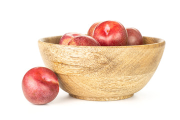 Lot of whole fresh pluot interspecific plums variety in a wooden bowl isolated on white