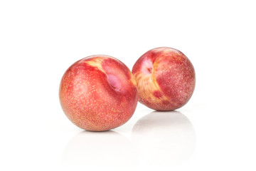 Group of two whole fresh pluot interspecific plums variety isolated on white