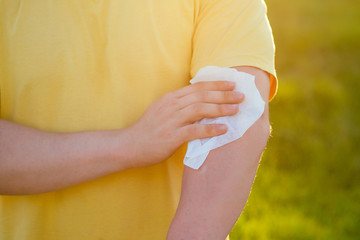 young man wipes his hands with a wet napkin on a yellow t-shirt background