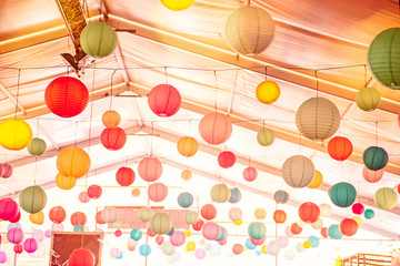 Bright background with many colorful chinese round lantern decorating the ceiling of hall at celebrating event, festival, party. Party decoration concept. Soft selective focus, copy space.
