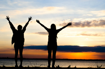 Couple woman silhouette standing very happily talking during sunset and beautiful sky.