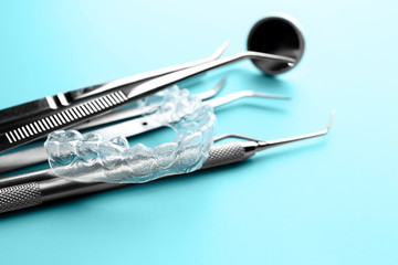 Dental instruments and occlusal splint on color background, closeup