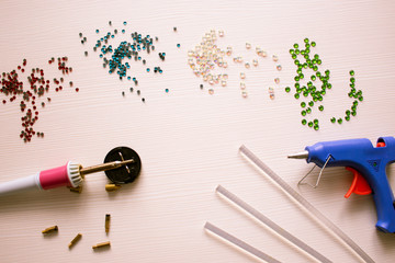 Workplace for handmade decoration. A set of rhinestones, glue gun and soldering iron