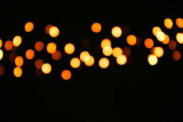 Christmas glowing lights on dark background, blurred view