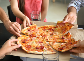 Young people taking slices of hot tasty pizza from cardboard box