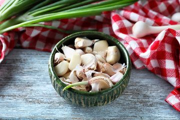 Bowl with fresh garlic on light wooden background