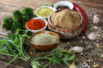 Various fresh herbs with dry spices on wooden table