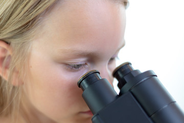 Ein 9 jähriges Mädchen schaut in das Okular eines Mikroskops. Freisteller