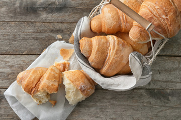 Basket with tasty croissants on wooden table
