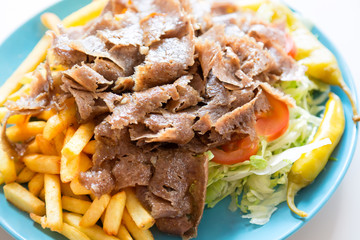 Turkish cuisine. Doner kebab meat with pommes frites potatoes and salad on plate. Close up with...