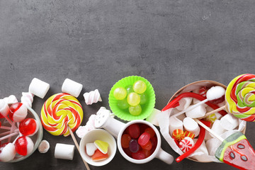 Colorful candies with marshmallows on grey background