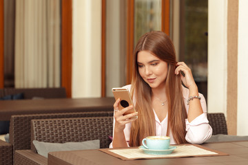 Portrait of beautiful girl using her mobile phone in cafe.