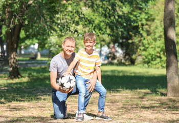 Fototapeta premium Happy father and son with soccer ball in park