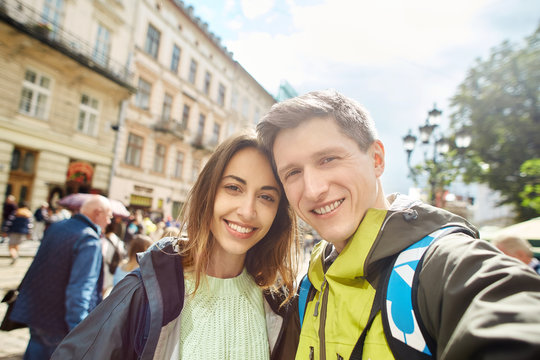 happy young couple of tourists walking on the center of the city and makes selfie