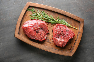 Fresh raw meat with rosemary and spices on wooden board