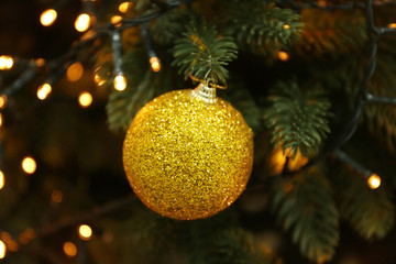 Obraz na płótnie Canvas Glowing lights and Christmas ball on fir tree