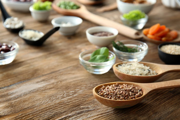 Spoon with buckwheat and healthy products on wooden table