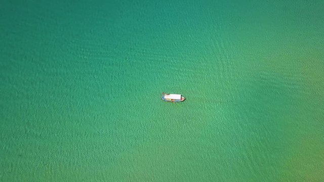 Fishing boat sailing in blue sea top view. Aerial landscape from flying drone ship sailing in transparent and turquoise ocean water.