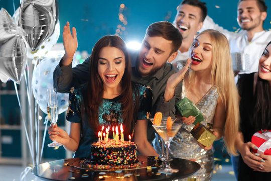 Young Woman With Friends Near Her Birthday Cake At Party In Club