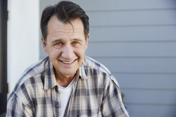 Obraz premium Portrait Of Senior Man Standing Outside Grey Clapboard House