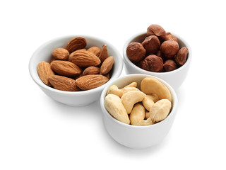 Bowls with different nuts on white background