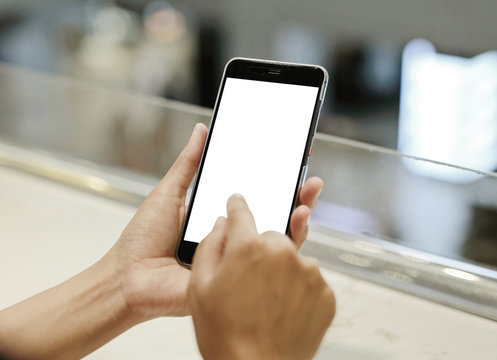 Close up hands of business woman holding smartphone with blank screen on the table.