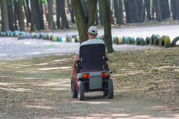 Disabled person on an electric carriage on walk in the park. People