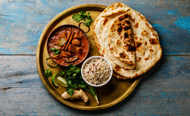Chicken tikka masala spicy curry meat food with rice and naan bread on wooden background