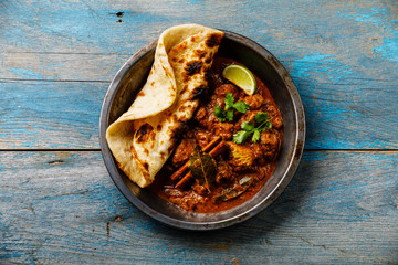 Chicken tikka masala spicy curry meat food and naan bread on blue wooden background - obrazy, fototapety, plakaty
