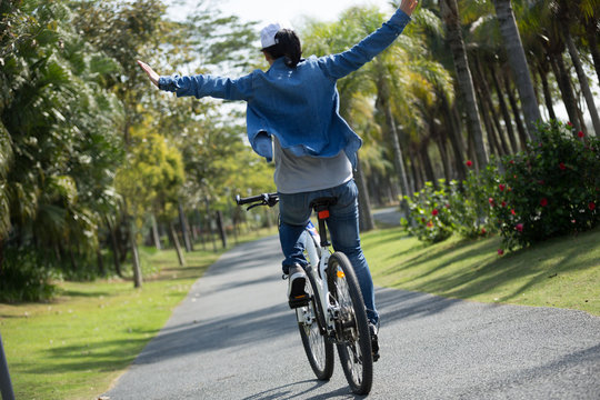 happy woman cyclist riding bike on tropical park
