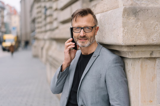 Middle-aged man smiling while talking on mobile
