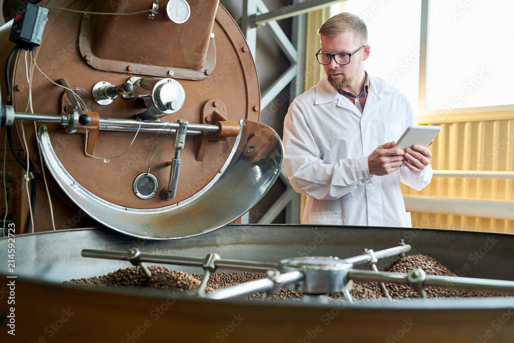 Wall mural Waist up portrait of modern worker wearing lab coat  working in coffee production manufactory, copy space